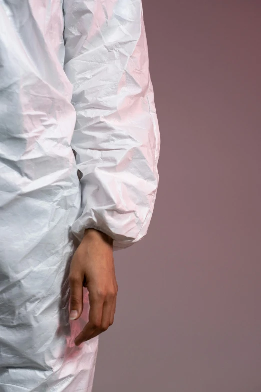 a close up of a person in a white coverall, by Nina Hamnett, trending on pexels, plasticien, made of lab tissue, voluminous sleeves, plain background, white and pink