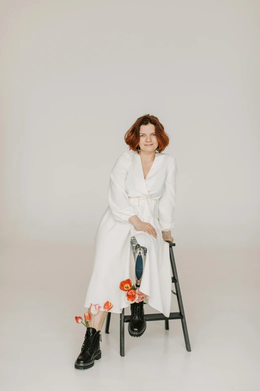 a woman sitting on a chair in a white room, an album cover, by Anita Malfatti, pexels contest winner, renaissance, white lab coat, woman with red hair, crutches, in a maxi white dress