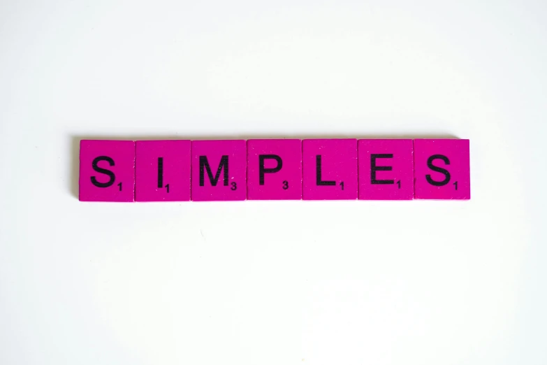a pink scrabble spelling the word simples, pexels, minimalism, temples, colorful signs, simple minimal, wesley kimler
