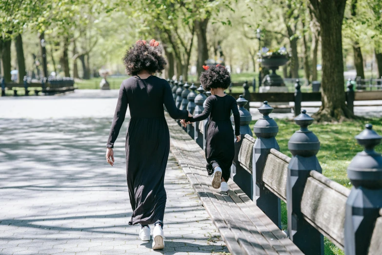 a woman and a child walking down a sidewalk, by Nina Hamnett, pexels contest winner, harlem renaissance, in the park, wearing a black dress, natural hair, long black ponytail