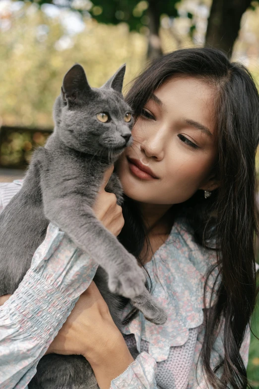 a woman holding a gray cat in her arms, trending on pexels, sumatraism, beautiful young asian woman, blue, 2 4 mp, ad image