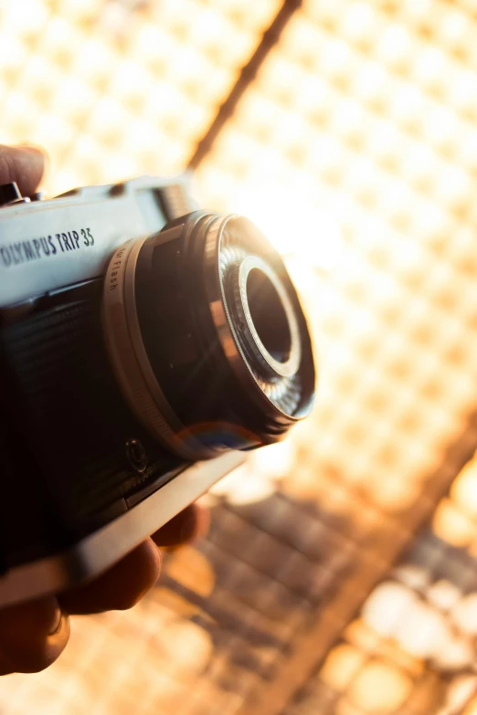 a close up of a person holding a camera, a picture, lensflare, fujifilm x - pro 2, olympus, back towards camera