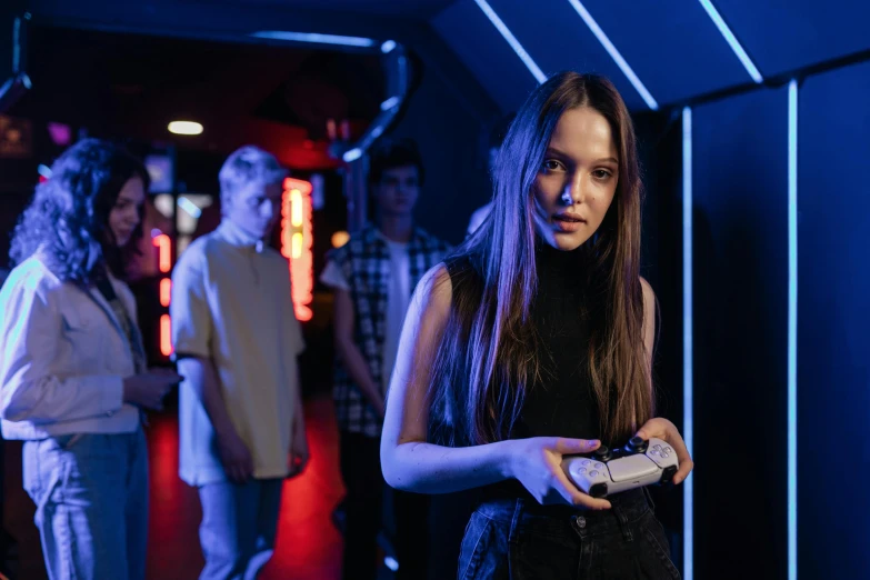 a woman in a black dress holding a cell phone, by Adam Marczyński, pexels contest winner, gaming room in 2 0 4 0, red and blue neon, teenagers, standing in a cantina