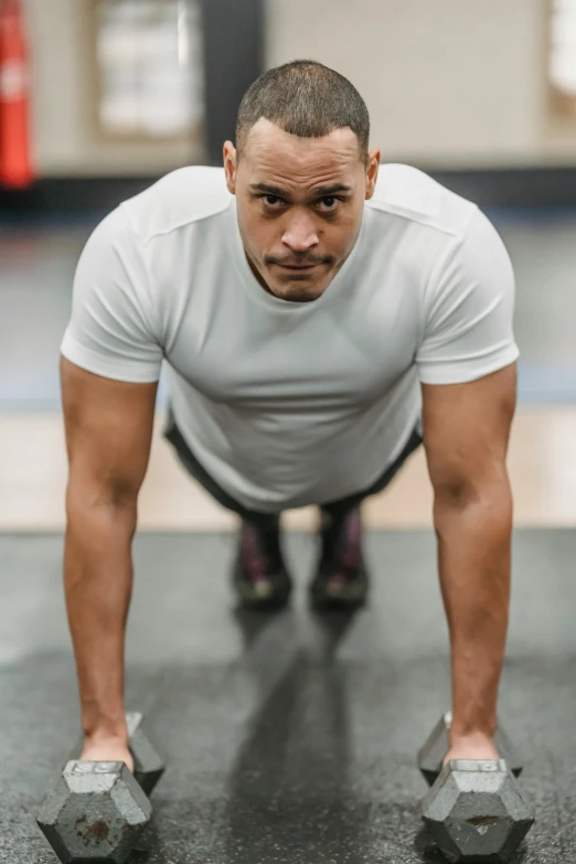 a man doing push ups with dumbbells in a gym, a portrait, pexels contest winner, renaissance, promo image, confident looking, plain background, ronaldo nazario