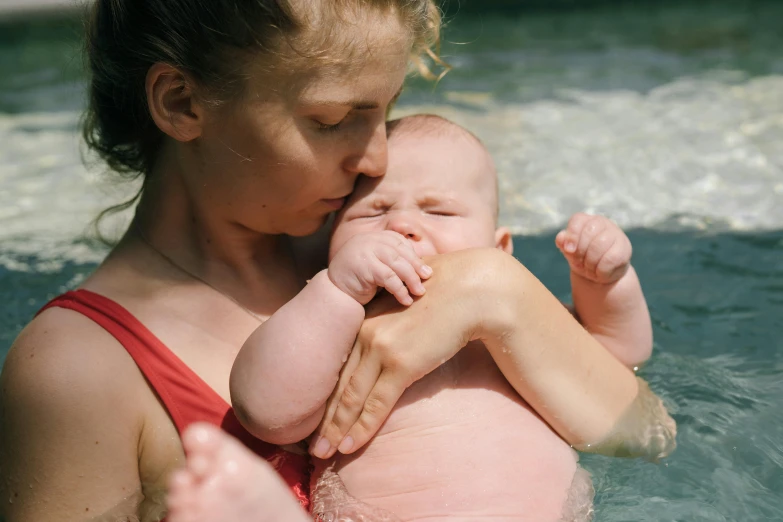 a woman holding a baby in a pool, pexels contest winner, comforting and familiar, bowater charlie and brom gerald, thumbnail, sunburn