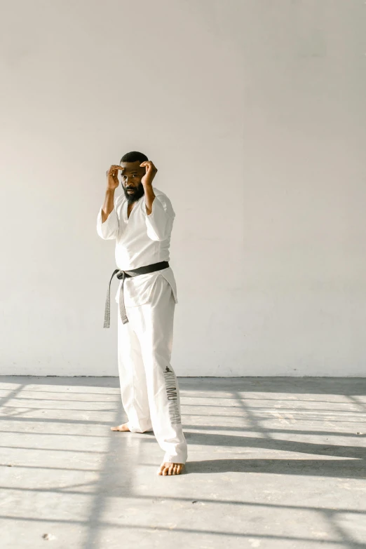 a man in a white kimono standing in a room, unsplash, happening, capoeira, wearing a track suit, full body hero, usa