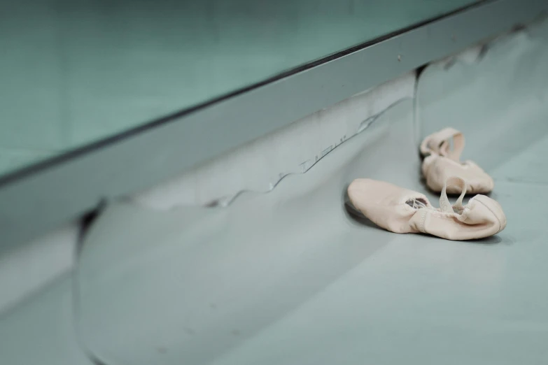 a pair of ballet shoes sitting on the floor, by Elsa Bleda, arabesque, at the counter, glassy fracture, silver，ivory, schools