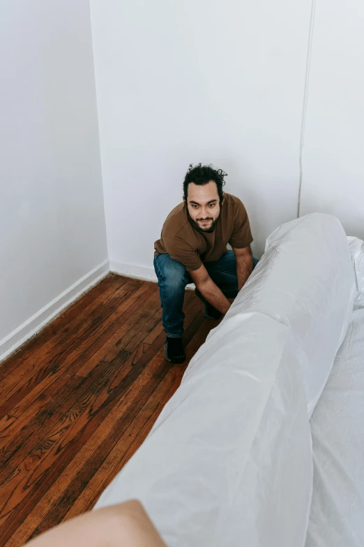 a man sitting on a bed in a room, an album cover, by Everett Warner, pexels contest winner, happening, furniture overturned, ariel perez, about to step on you, cramped new york apartment