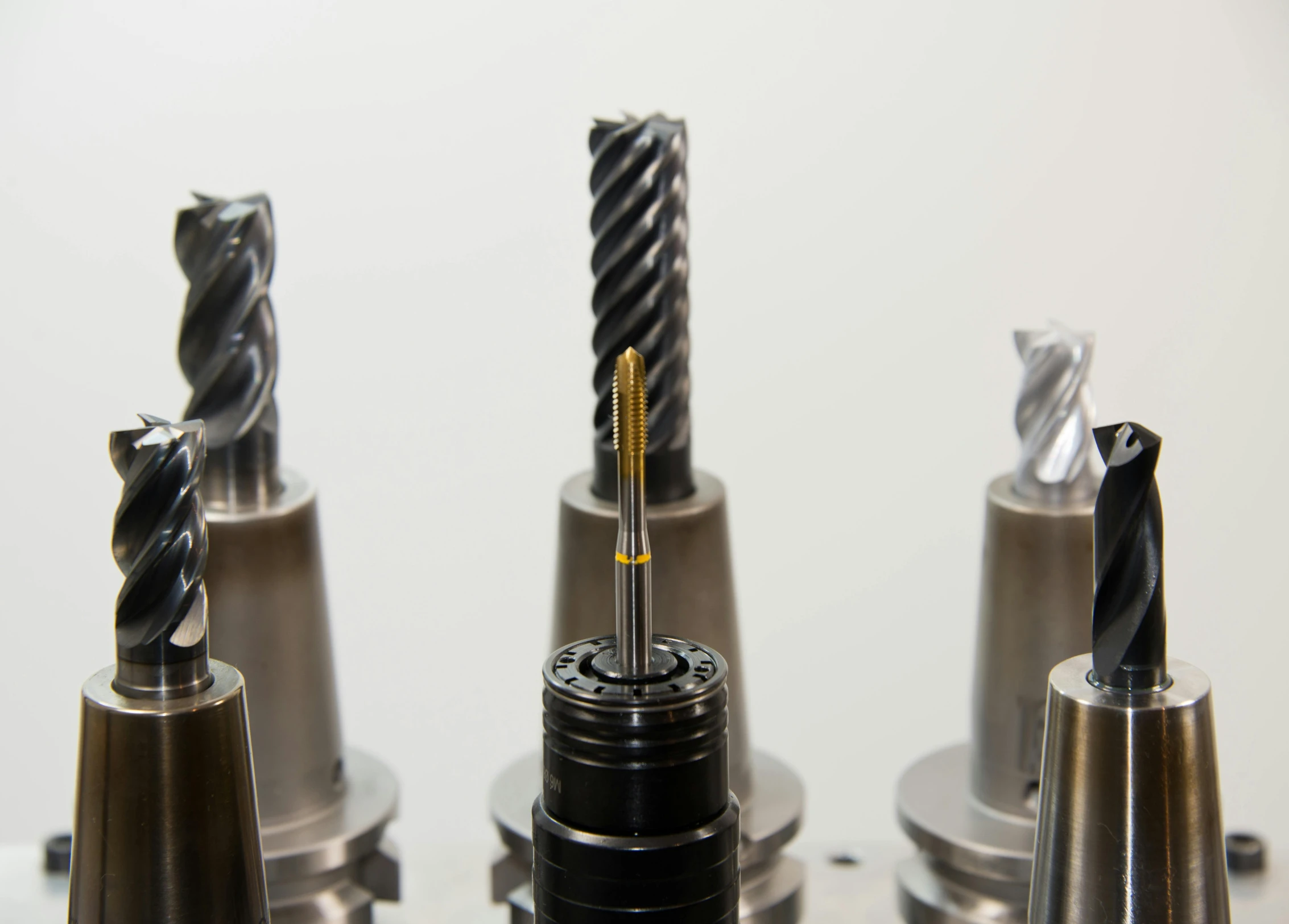 a group of drill heads sitting on top of a table, a stipple, unsplash, photorealism, tungsten, spire, lathe, close - up profile