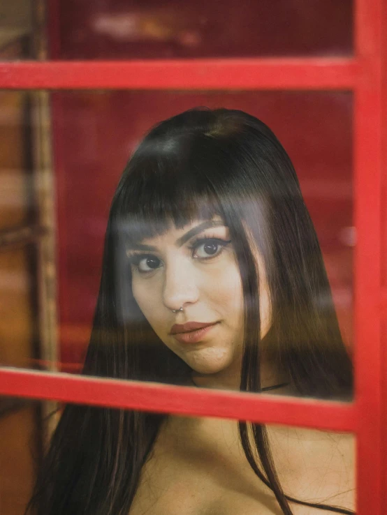 a woman standing in front of a red phone booth, an album cover, inspired by Elsa Bleda, closeup headshot, charli xcx, looking out window, straight fringe