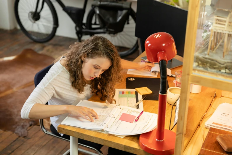 a woman sitting at a desk writing on a piece of paper, by Jessie Algie, ultrastation hq, engineer, indi creates, profile image