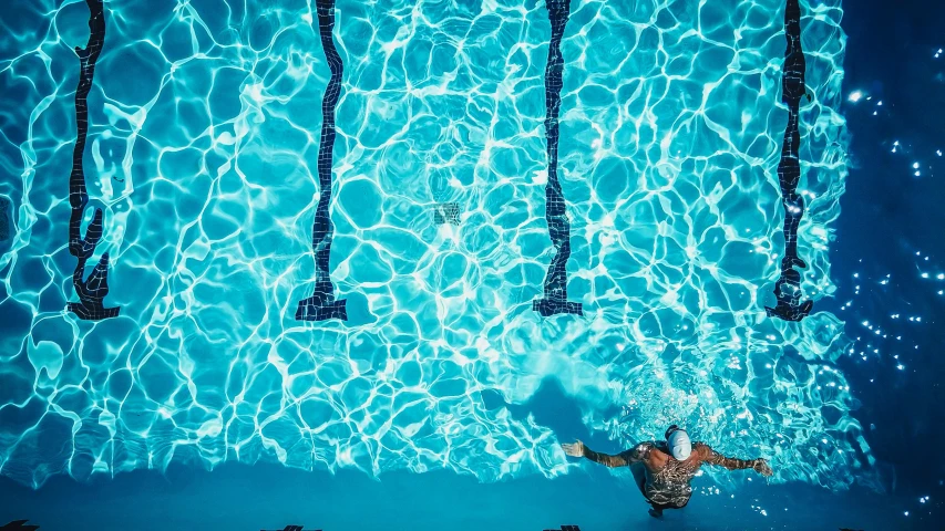 a man swimming under the water in a pool, by Daniel Lieske, unsplash contest winner, fine art, fan favorite, poolside, drone photograph, pools of water