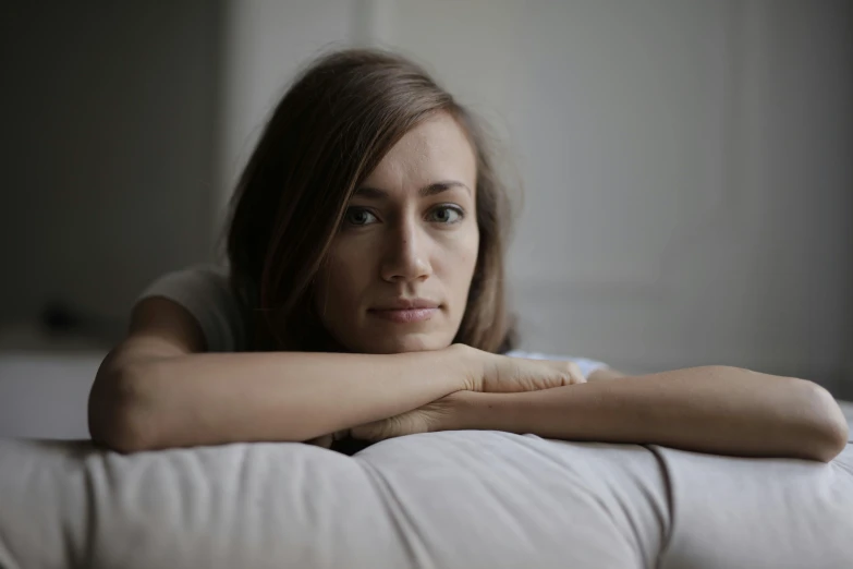 a woman sitting on top of a white couch, pexels, sad face, someone sits in bed, close up portrait photo, mid 2 0's female