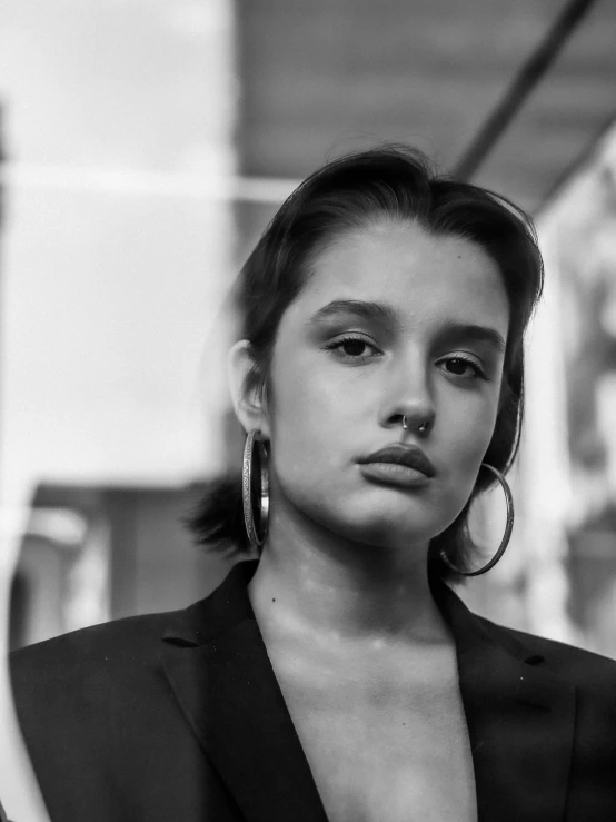 a black and white photo of a woman in a suit, a black and white photo, by Emma Andijewska, pexels contest winner, photorealism, isabela moner, huge earrings and queer make up, woman in streetwear, joey king