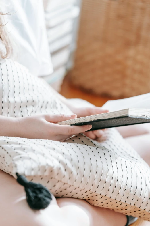 a woman sitting on a bed reading a book, trending on pexels, pregnant belly, zoomed in, holding notebook, digital image