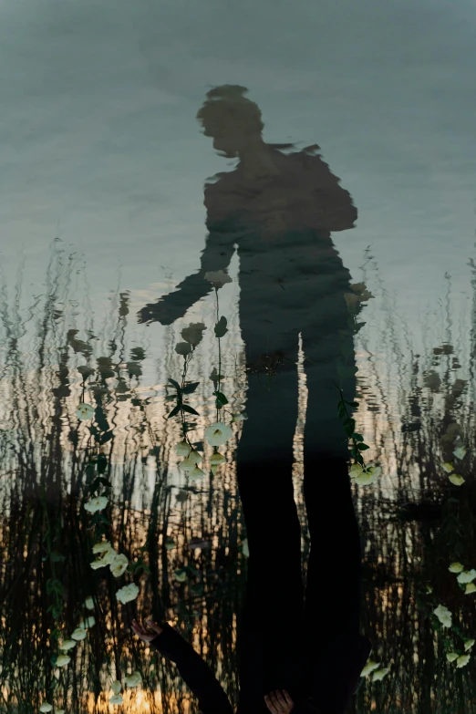a person standing in front of a body of water, by Attila Meszlenyi, conceptual art, silhouettes in field behind, reflect photograph, digital image, musician