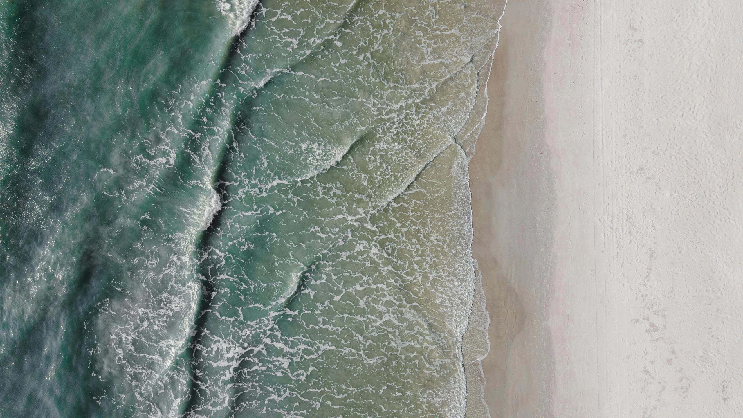 a person riding a surfboard on top of a sandy beach, inspired by Andreas Gursky, unsplash contest winner, photorealism, extremely detailed water texture, the emerald coast, seen from straight above, intricate flowing paint