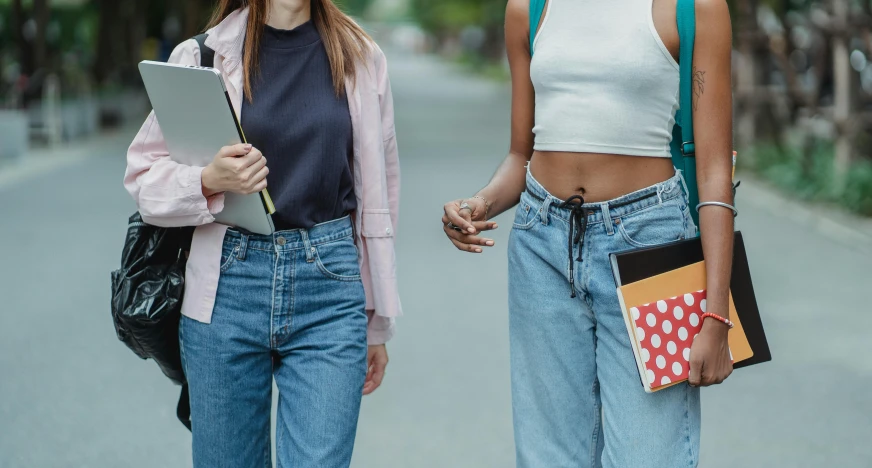 a couple of women walking down a street next to each other, trending on pexels, happening, physical : tinyest midriff ever, standing in class, teenage female schoolgirl, blue jeans