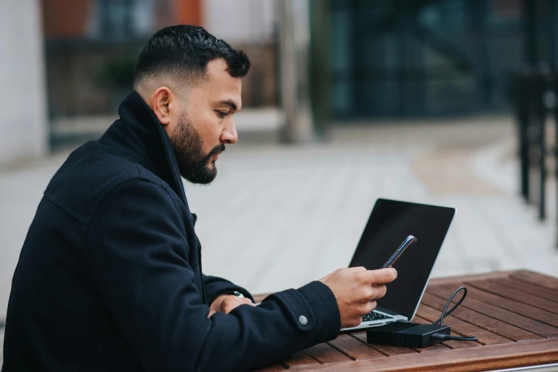 a man sitting at a table using a laptop computer, pexels contest winner, holding a very advance phone, avatar image, outdoors business portrait, profile image