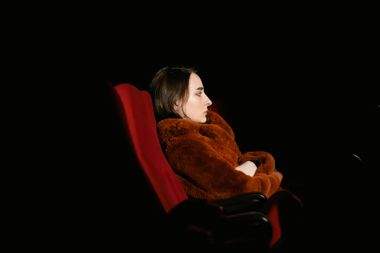 a woman sitting in a chair with a teddy bear, an album cover, inspired by Elsa Bleda, trending on pexels, visual art, lilly collins, red fabric coat, sitting in a movie theater, showstudio