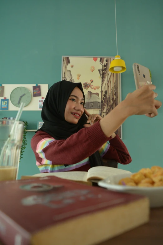 a woman sitting at a table taking a picture of herself, inspired by JoWOnder, realism, islamic, film still promotional image, home video, cute scene