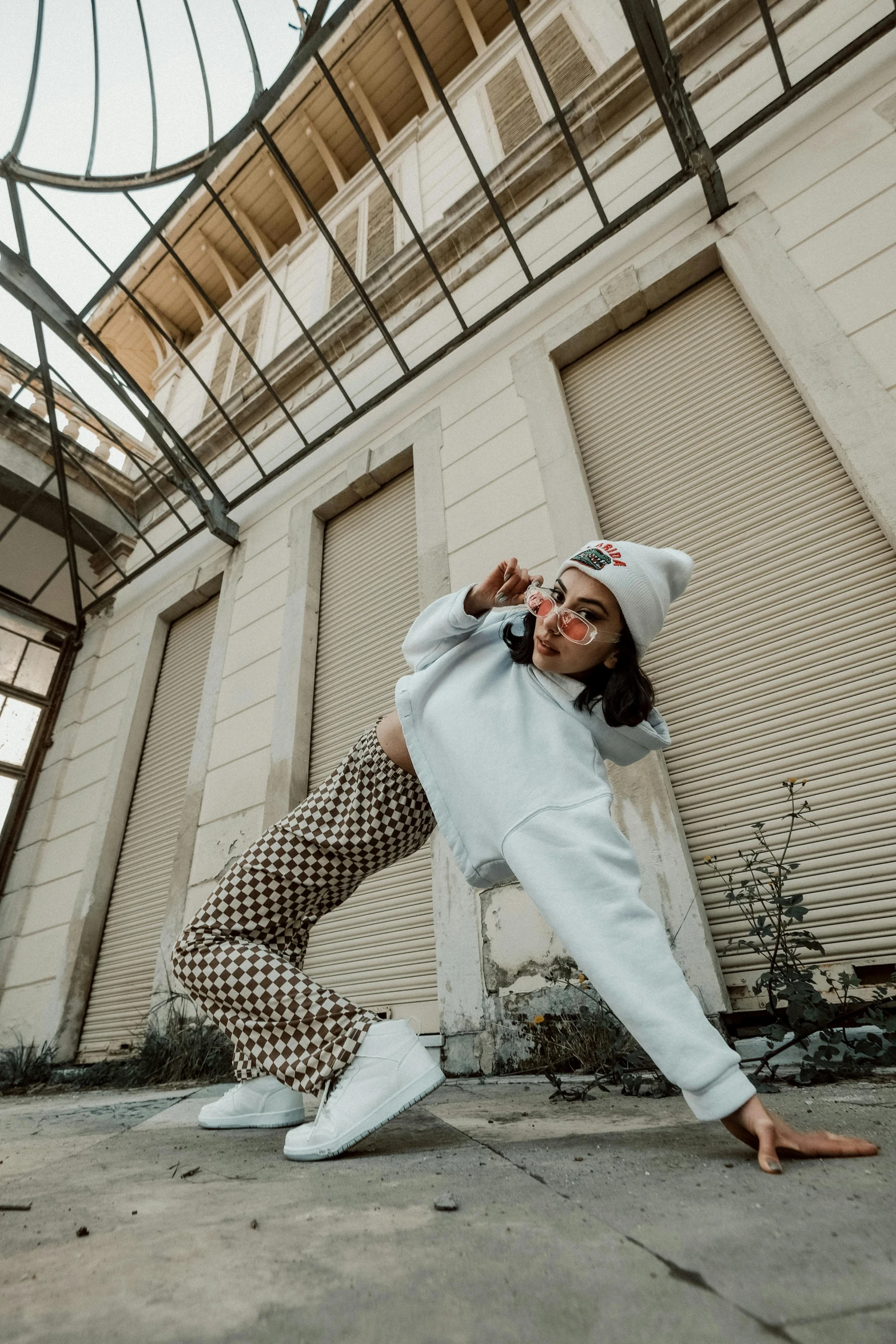 a woman doing a yoga pose in front of a building, trending on pexels, graffiti, wearing a white sweater, doing a sassy pose, on a checkered floor, rapping