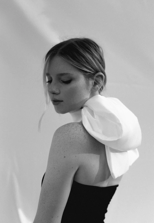 a black and white photo of a woman in a dress, by Emily Shanks, ellie bamber, showing her shoulder from back, wide ribbons, profile posing