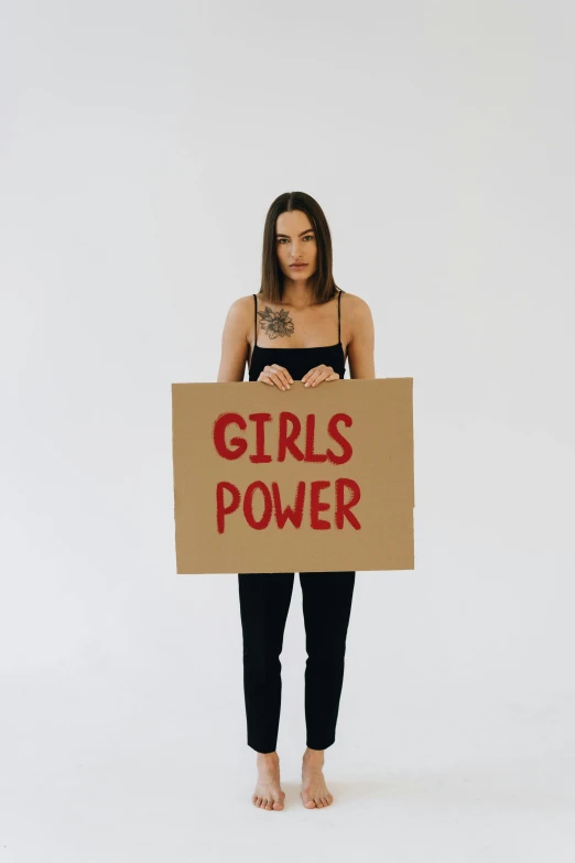 a woman holding a sign that says girls power, trending on pexels, full-body, instagram post, alessio albi, gal gadot