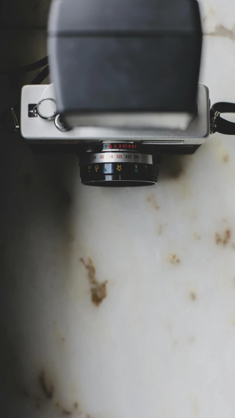 a close up of a camera on a table, by Peter Churcher, unsplash contest winner, vintage soft grainy, on a gray background, sink, a high angle shot