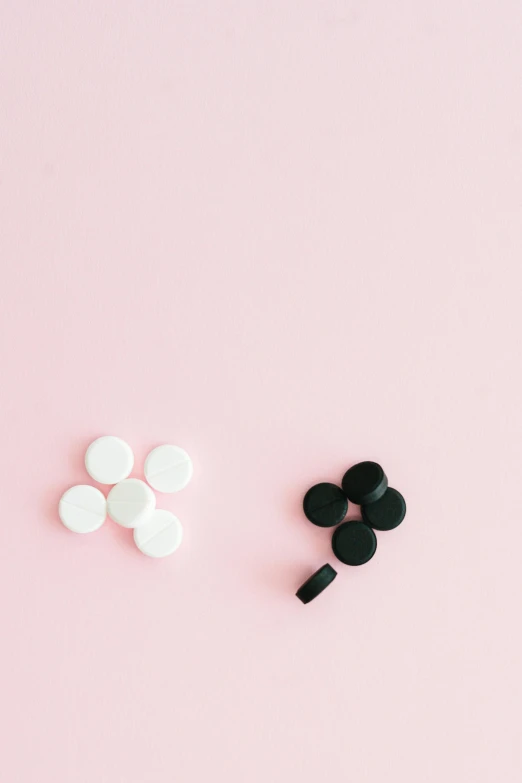 a pair of black and white hair clips on a pink background, by Nicolette Macnamara, unsplash, pills, sleek round shapes, black color on white background, milk cubes