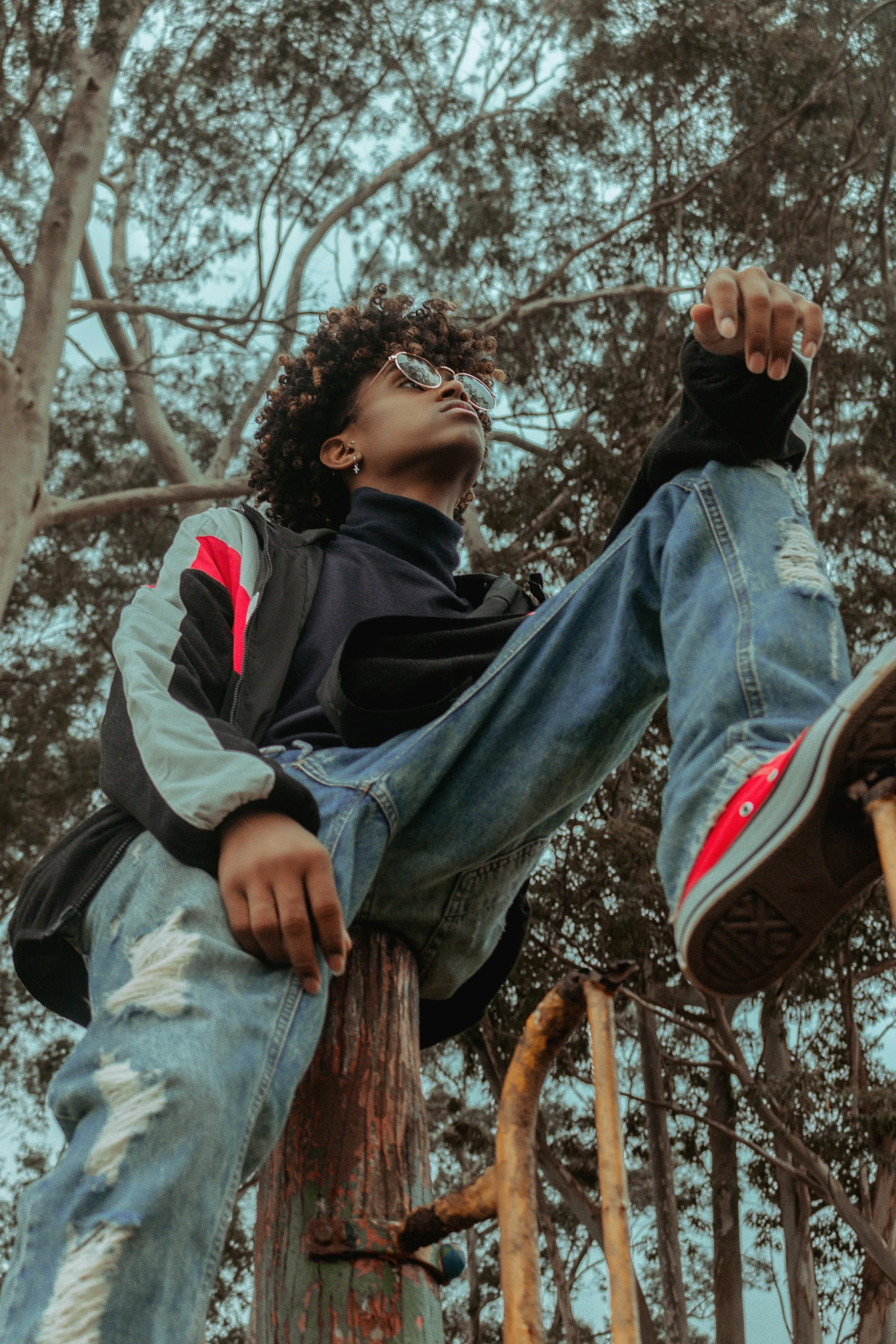 a man sitting on top of a wooden pole, an album cover, trending on pexels, ashteroth, sneaker photo, badass pose, with trees