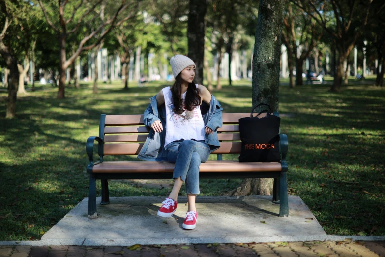 a woman sitting on a bench in a park, inspired by Gang Hui-an, pexels contest winner, ootd, moe, crimson themed, denim