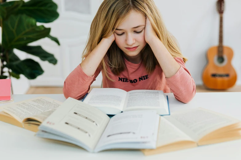 a young girl sitting at a table reading a book, pexels contest winner, tired half closed, 2263539546], educational supplies, teenager girl