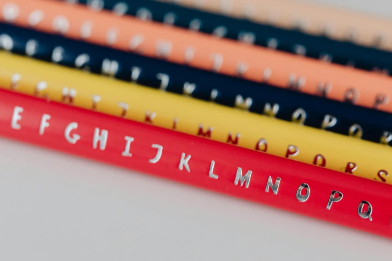 a group of pencils sitting on top of each other, unsplash, letterism, primary colours, detailed letters, rubber hose, engraved