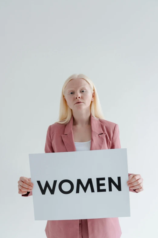 a woman holding a sign that says women, intense albino, profile image, high-quality photo, human staring blankly ahead