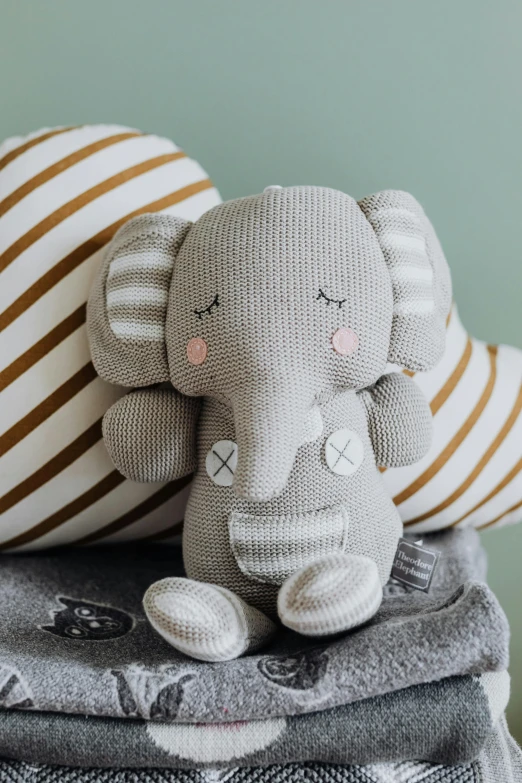 a stuffed elephant sitting on top of a stack of blankets, inspired by Károly Brocky, pexels contest winner, grey and silver, stripes, eucalyptus, my little everything