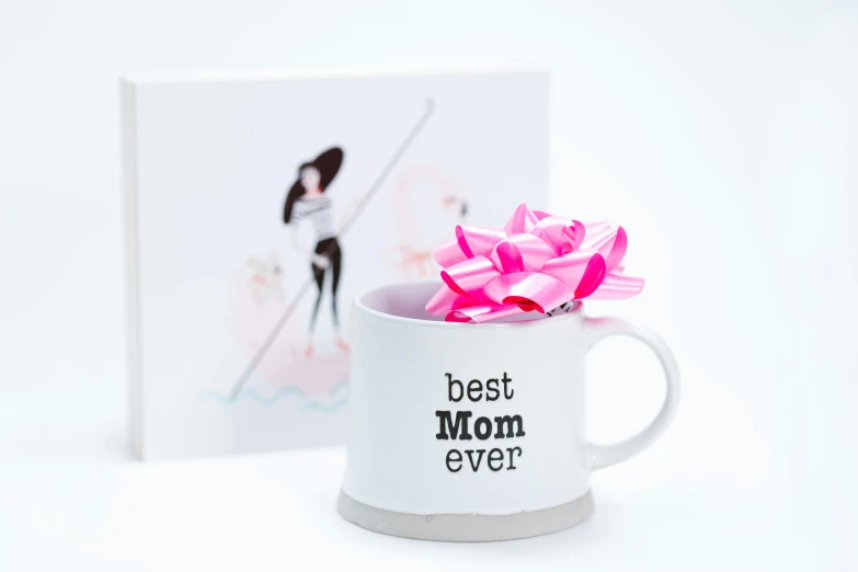 a white coffee mug with a pink flower in it, pop figure of mom with long, holding a bow, the best ever, product introduction photo