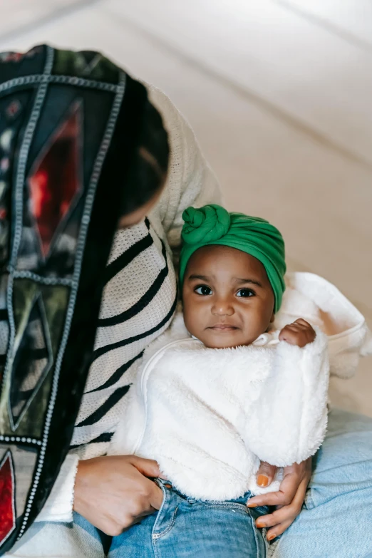 a woman holding a baby wearing a green turban, by Nina Hamnett, trending on unsplash, virgil abloh, : kendrick lamar, little kid, cloth wraps