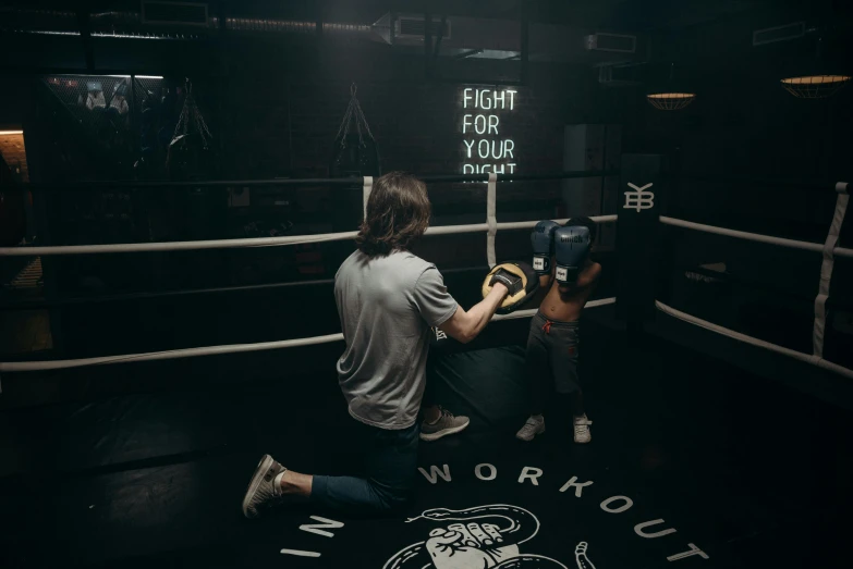 a man standing next to a little boy in a boxing ring, by Emma Andijewska, unsplash contest winner, working out, kneeling, pitch black room, 8k in the style