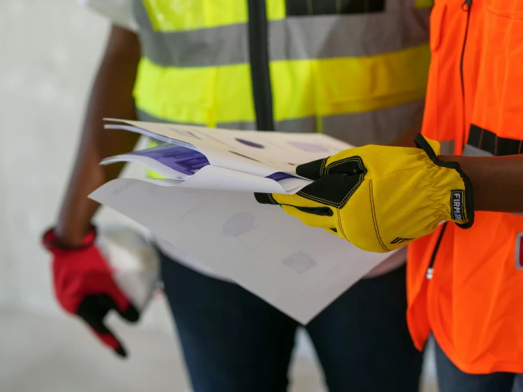 two construction workers standing next to each other, pexels contest winner, delivering mail, gloves on hands, reflective vest, on paper