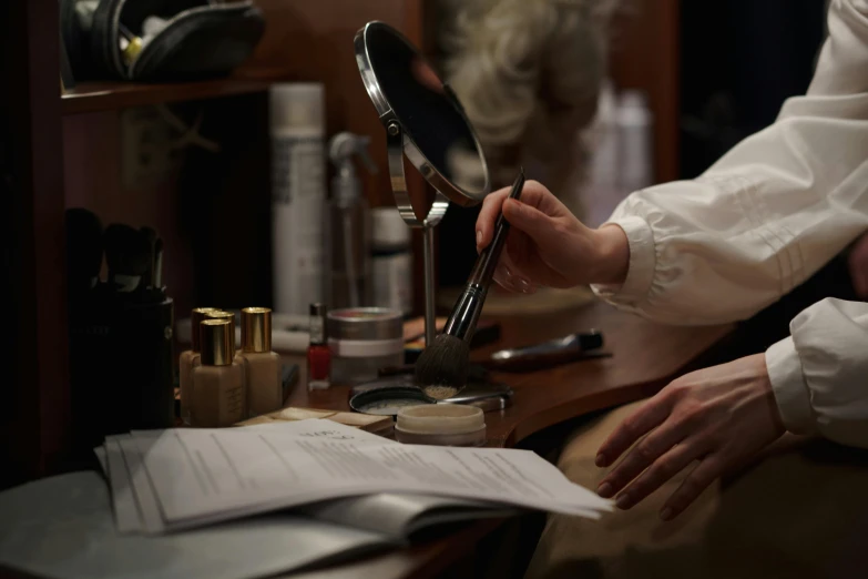 a man sitting at a desk in front of a mirror, ivory make up, precisely drawn, production photo, zoomed in