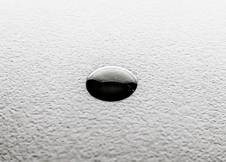 a black and white photo of a hole in a wall, a stipple, inspired by Lucio Fontana, unsplash, minimalism, water bubble, floor fog, 2 8 mm macro photo, oil on canvas high angle view