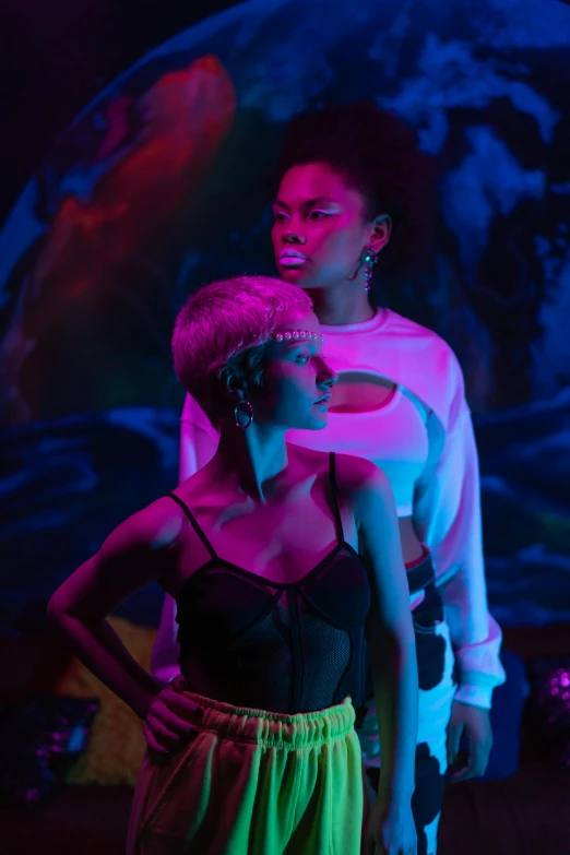 a couple of people standing next to each other, afrofuturism, purple scene lighting, woman holding another woman, [ theatrical ]