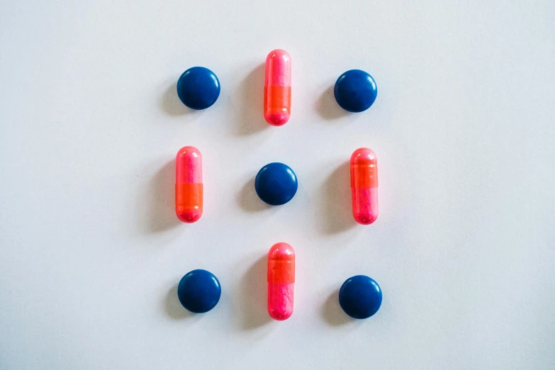 a group of red and blue pills on a white surface, inspired by Évariste Vital Luminais, unsplash, antipodeans, featuring pink brains, bullet tracers, dark blue + dark orange, made of plastic