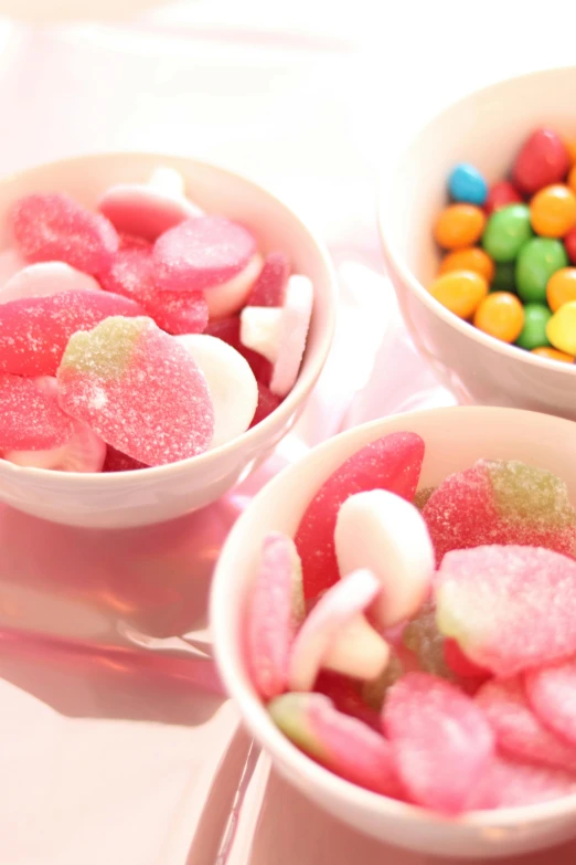 three bowls of candy sitting on top of a table, gumdrops, pinks, london, parties