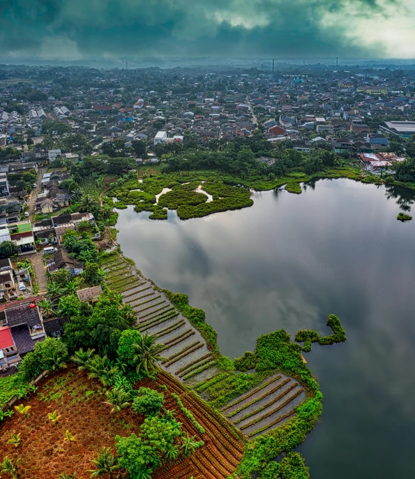 a large body of water sitting on top of a lush green hillside, an album cover, by Basuki Abdullah, pexels contest winner, sumatraism, drone view of a city, an aztec city in a island lake, assamese, bioremediation