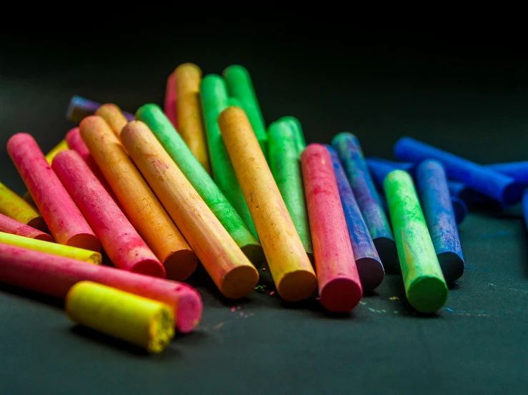 a pile of crayon sticks sitting on top of a table, chalk art, by Robert Richenburg, pexels, in front of a black background, chalked, thumbnail, colored projections