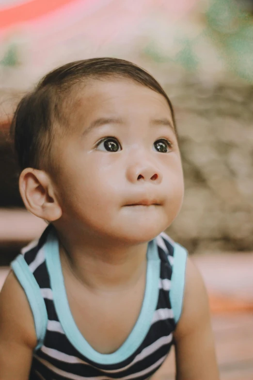 a baby sitting on the ground looking up, pexels contest winner, sumatraism, closeup at the face, confident looking, looking off into the distance, boy has short black hair