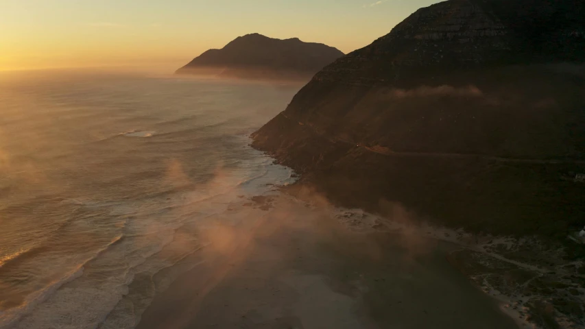 a view of the ocean from the top of a mountain, by Daniel Lieske, pexels contest winner, land art, flying through sunset, sand mists, cape, aerial footage