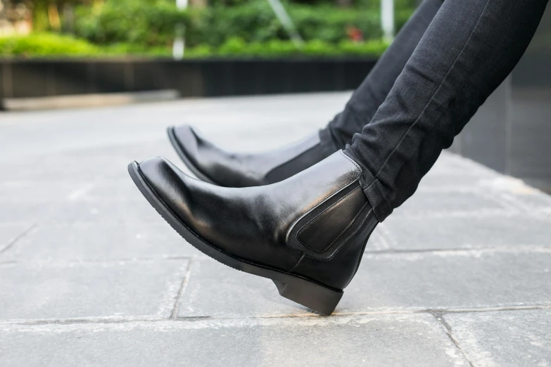 a close up of a person wearing black boots, product view, sharply shaped, on the street, medium angle